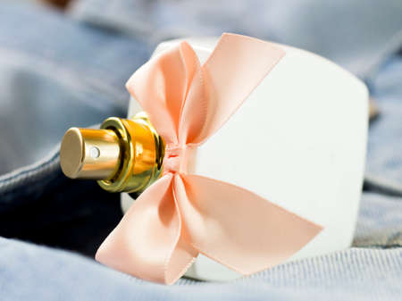 White perfume bottle with pink bow on denimの写真素材
