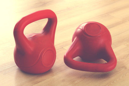 Two kettlebells stand on a wooden floorの写真素材