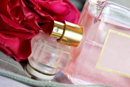 Perfume bottle and red rose close-up. Perfumery concept