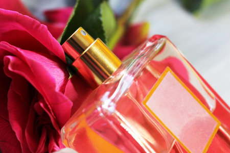 Bottle of perfume and roses, close-up, on light background