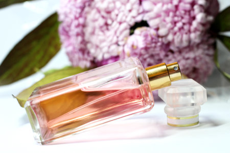 Perfume bottle and pink peony flowers on white background.の写真素材
