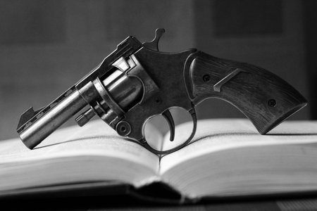 Revolver and open book on a dark background. Black and white photo.の写真素材