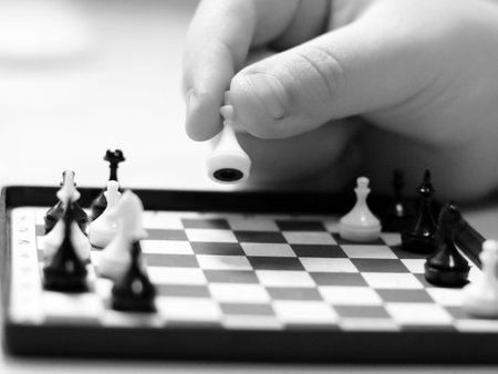 Close-up image of hand playing chess. Black and white photo.