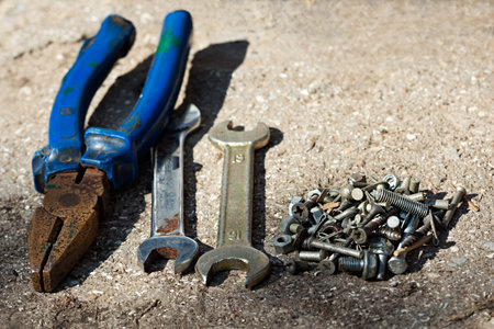 Old pliers, wrenches, screws on the concrete floor. A set of tools for installation and repair....