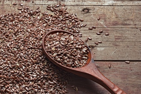 Flax seeds on a rough wooden background and a spoon. Healthy products, a source of vitamins and essential fatty acids, the raw material for oil. Still life photo.の写真素材
