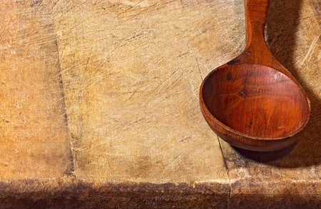 Empty wooden spoon lying on a rough wooden background. Rural style still live close up image with copyspace.の写真素材