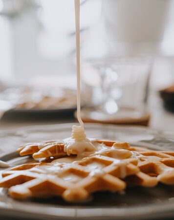 Condensed milk is poured onto Viennese wafflesの写真素材