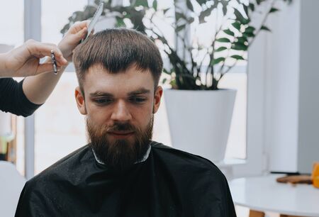 Mens haircut at home. The hairdresser cuts the hair of a manの写真素材