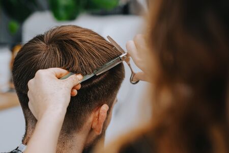 Mens haircut at home. The hairdresser cuts the hair of a manの写真素材