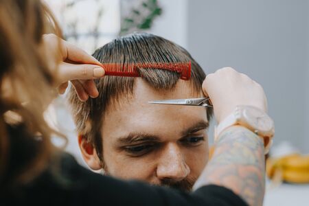 Mens haircut at home. The hairdresser cuts the hair of a manの写真素材