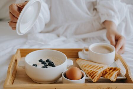 Breakfast in the hotel. Girl opens a pan with porridgeの写真素材