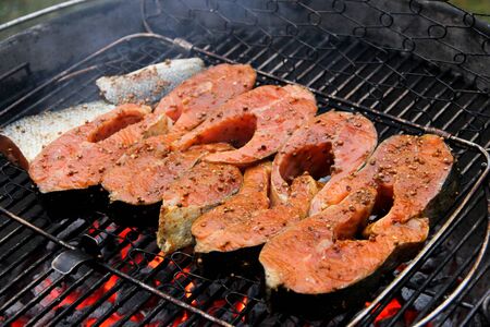 Salmon filet in teriyaki sauce on a barbeque grid. Red fish steaks in marinade over hot coals. Close-up of a grilled salmon steaks in barbeque grill.の写真素材