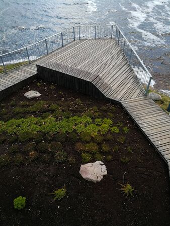 Wooden pier that leads to a viewing platform. Wooden site in front of the river. Wooden walk board with a fence in a cloudy day.の写真素材