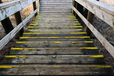 Old wooden stairway that go down. Going down stairs during outdoor walking. Aged wooden boards at a hiking trail.の写真素材