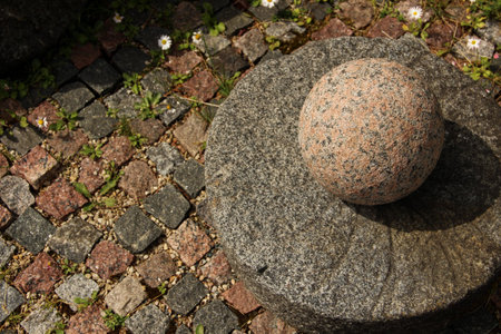 Decorative granite ball and round base on a pavement.