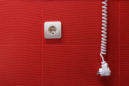 Conceptual red background with a white plug and socket installation.の写真素材