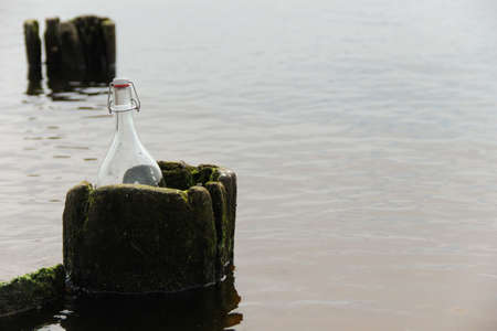 Glass bottle placed into an old wooden beam. Symbol of undiscovered.の写真素材