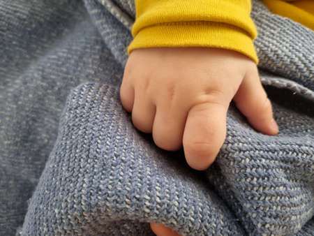 Baby's hand over blue blanket. Sentimental moment with a resting toddler. Tiny hand of a newborn son. Baby's pacifier at the background.の写真素材