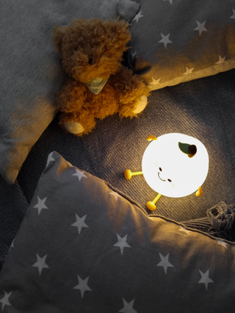 Kids' night light among pillows and toys. Turned on the night light. Cozy shelter for a little toddler. A cute flashlight that illuminates the nursery room.の写真素材