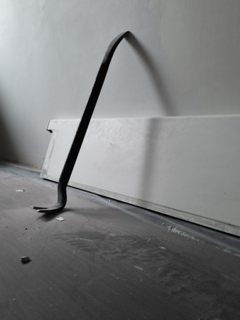 Close up of a used crowbar. Use of scrap for repair work in the house. Floor covering for protection during the house repair works. Iron scrap leaning against the wall.の写真素材