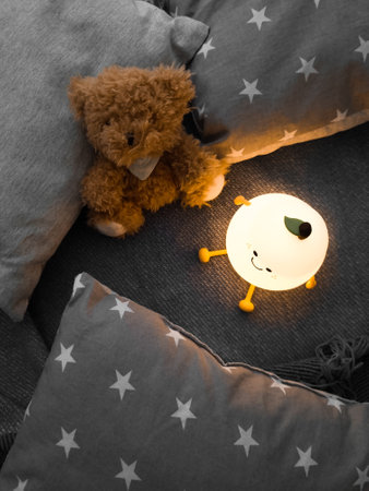 Kids' night light among pillows and toys. Turned on the night light. Cozy shelter for a little toddler. A cute flashlight that illuminates the nursery room.の写真素材