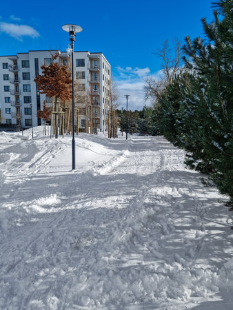 Luxury neighborhood with multi-storey buildings. Downtown apartments with a private courtyard. Sunny winter day at a modern apartment complex with unclean footpaths.の写真素材