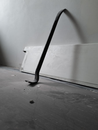 Close up of a used crowbar. Use of scrap for repair work in the house. Floor covering for protection during the house repair works. Iron scrap leaning against the wall.の写真素材