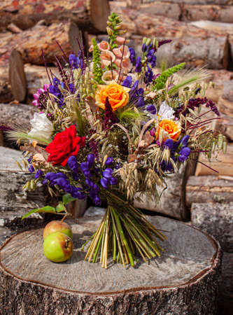Photo still life of a rural bouquet of flowers on a rhythmic background of logs with applesの写真素材