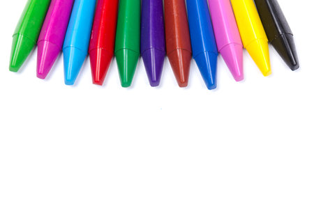 Bright colored wax pencils are scattered in a pile on white background in close upの写真素材