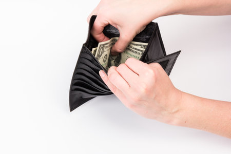 Closeup of top view leather black wallet with dollar banknote in female hands on white background. Concept for financial news, savings, povertyの写真素材