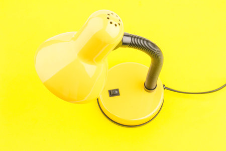 Yellow desk lamp isolated on yellow background. The concept of day and nightの写真素材