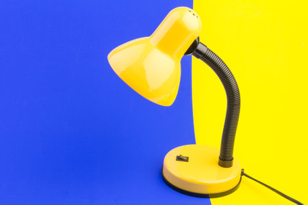 Yellow desk lamp isolated on blue and yellow background. The concept of day and nightの写真素材