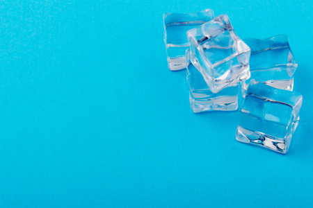 Pyramid of transparent ice cubes. Ice cubes close up on a blue background. space for textの写真素材