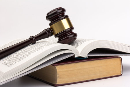 Brown wooden judges gavel on on gray background in close up. Wooden table, books. Space for text....