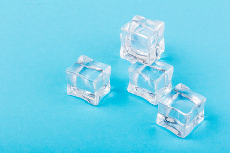Pyramid of transparent ice cubes. Ice cubes close up on a blue background. space for textの写真素材