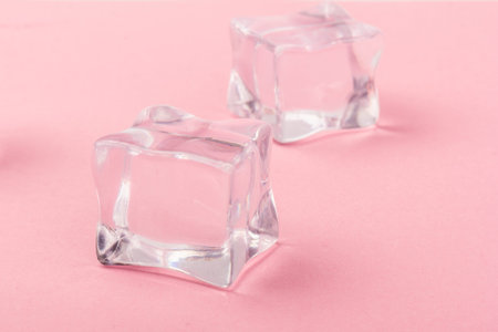 Pyramid of transparent ice cubes. Ice cubes close up on a pink background. space for text