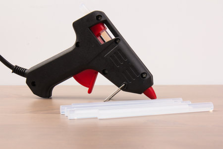 Hot-melt gun, construction tools. Glue gun and rods on wooden background.の写真素材