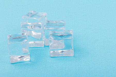 Pyramid of transparent ice cubes. Ice cubes close up on a blue background. space for text