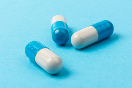 Blue and white capsules on blue background. Global healthcare concept. Pharmaceutical industry.の写真素材