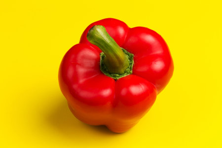 Juicy, bright and beautiful one red bell pepper on yellow background close-up