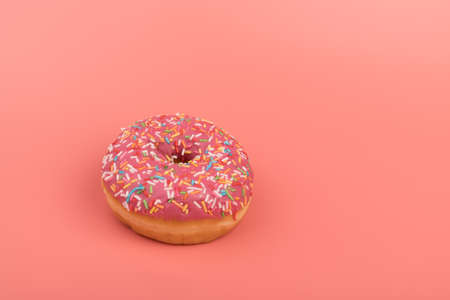 Donuts with strawberry icing and multicolored sprinkles, isolated on pink background. Traditional sweet pastries. Place for text.の写真素材