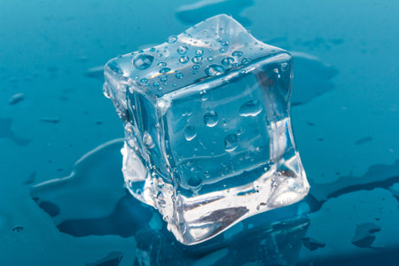 one melted ice cubes with drops. ice cubes and water drops close up on blue background