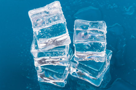 Pyramid of the melted ice cubes with drops.ice cubes and water drops close up on blue backgroundの写真素材