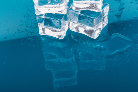melted ice cubes with drops. ice cubes and water drops close up on blue backgroundの写真素材