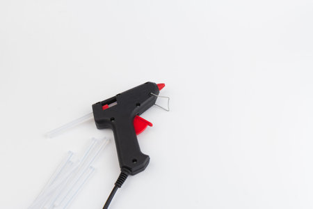 Hot-melt gun, construction tools. Glue gun and rods on gray background