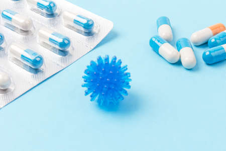Blue and white capsules and orange whith white capsules on blue background. Global healthcare concept Antimicrobial capsule pills. Pharmaceutical industry.の写真素材