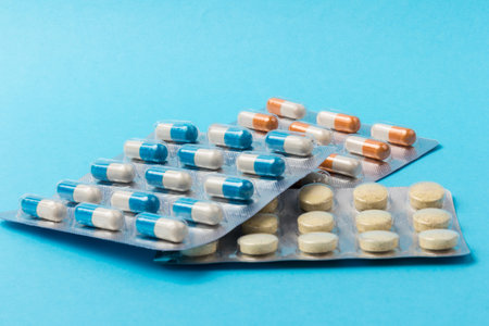 Orange and white capsules pill on blue background. Copy space. Global healthcare concept....
