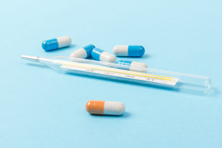 Blue and white capsules and orange whith white capsule pill on blue background. Copy space. Global...