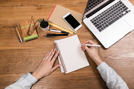 Work from home concept. Planner using phone and laptop to plan daily agenda on calendar book. Woman...