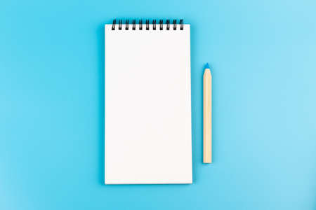 multicolor pencils and blank notebook on blue background with copy spaceの写真素材